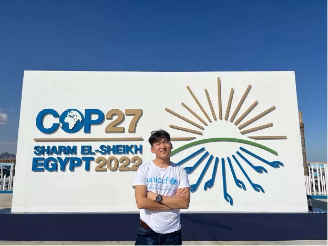 Youth delegate Garid Mendbayar standing in front of the COP27 Sharm el-Sheikh board, 10 November