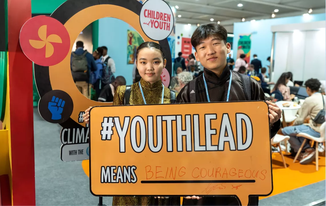 Garid at COP27 holding a sign with hashtag YouthLead