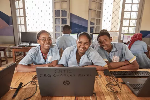 Three children use a school computer with internet access in Madagascar