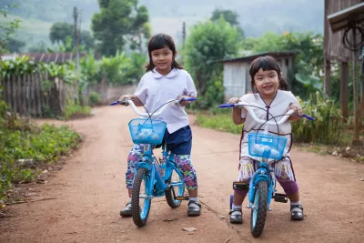 Two girls on a bicycle infront of their house
