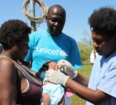 a unicef staff member with a baby in Vanuatu after a cyclone struck