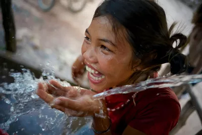A girl smiles while drinking water at a water point in the village of Adone, Ta Oi District, Saravane Province. The village is home to the Pacoh ethnic group.