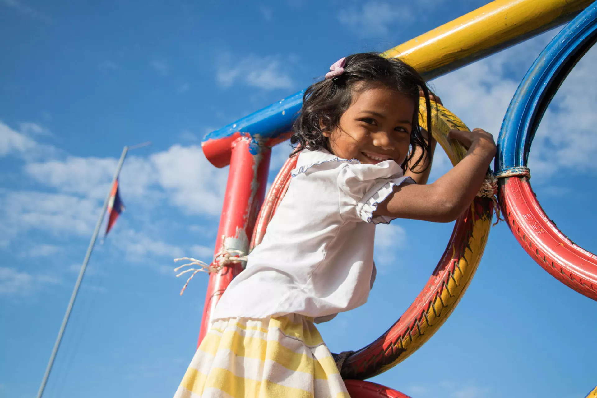 A girl enjoys playing in the playground at Srae Tahen primary school, Cambodia