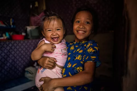 A girl holds her 13-month-old niece Jonaila inside their house. The next day Jonaila will receive her first vaccines.