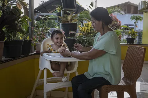 A grandmother feeds nutritious food to her one-year-old granddaughter at home