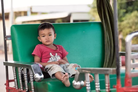 A boy is sitting, waiting for a tuk tuk driver to go to Siem Reap town