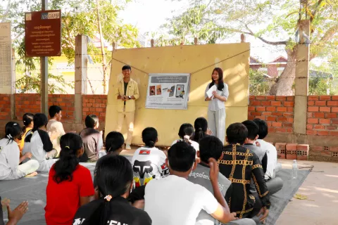 Young people gathered in the shade in Keo Por Commune in Cambodia to listen to two youth volunteers raising awareness about protection from online abuse and exploitation. 