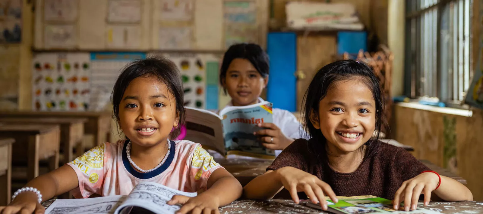 Students reading their workbooks in a classroom in Cambodia