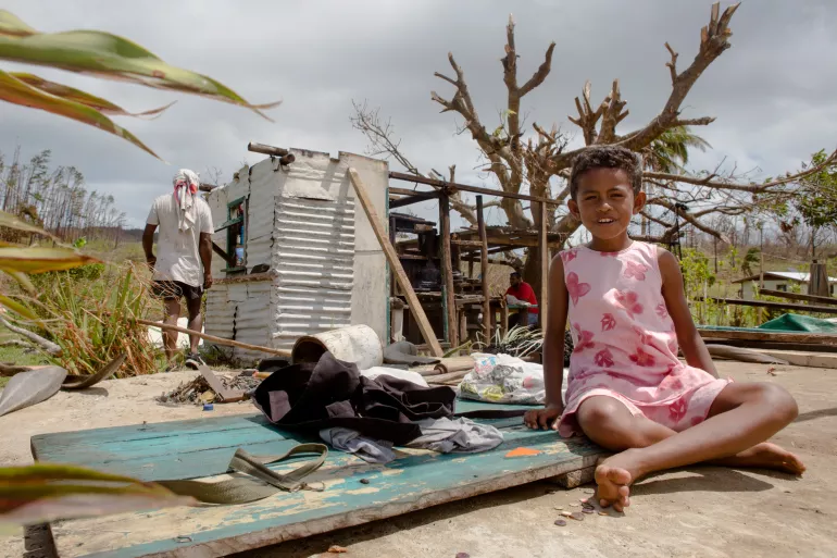 Nine-year-old Temo from Fiji sits by her family’s house that was destroyed by a cyclone. 