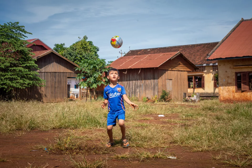A 6-year-old plays with a ball outside his home in Rattanakiri, Cambodia