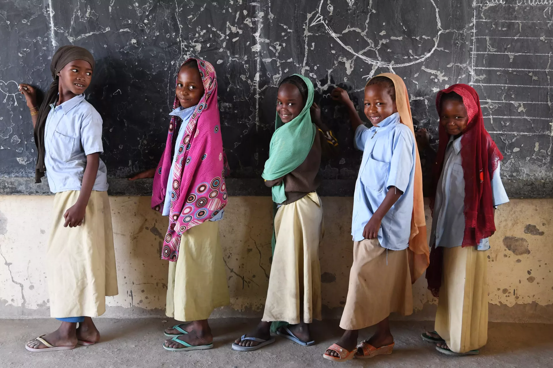 Children standing at a classroom blackboard