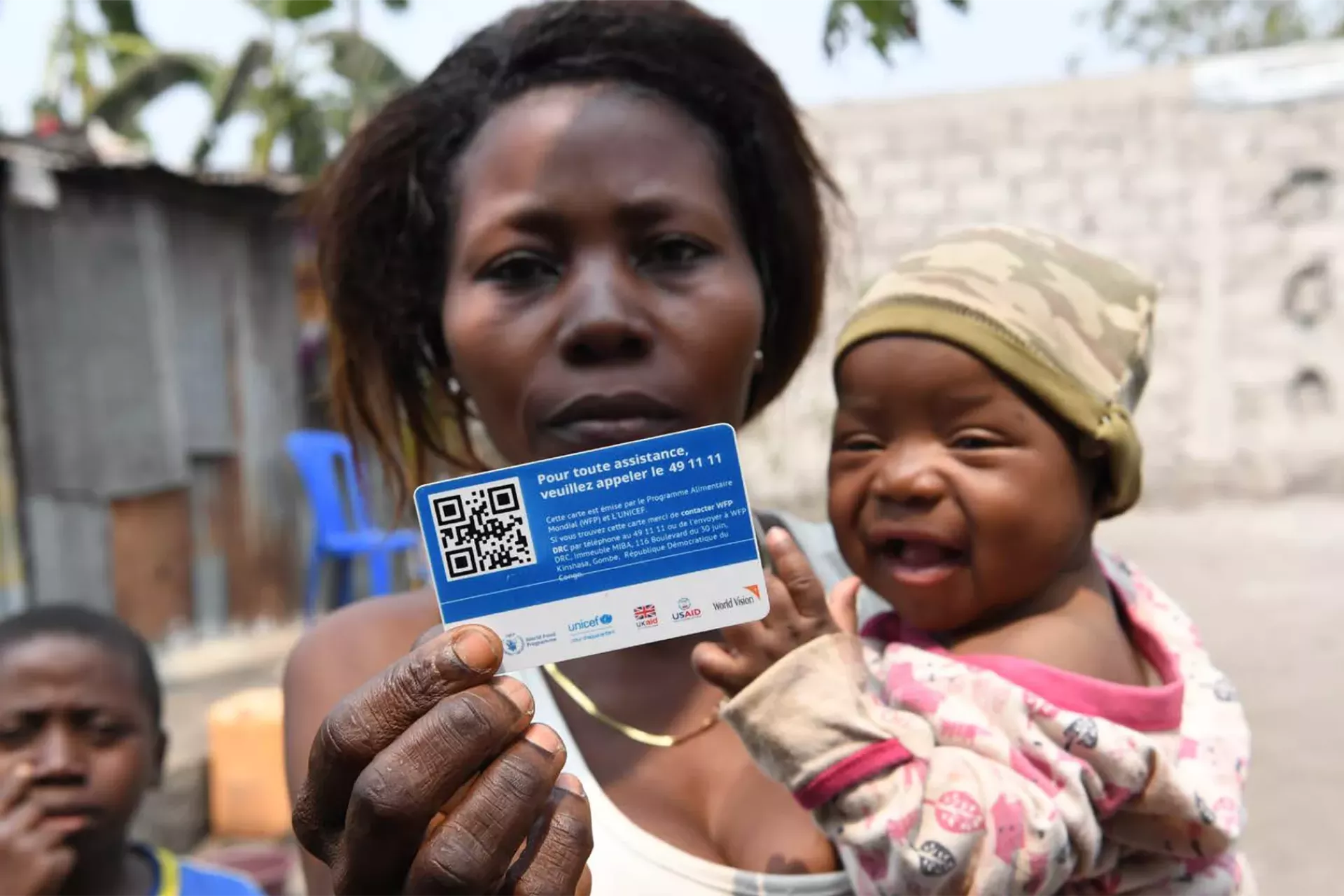 A woman, who is holding a baby, holds up a card