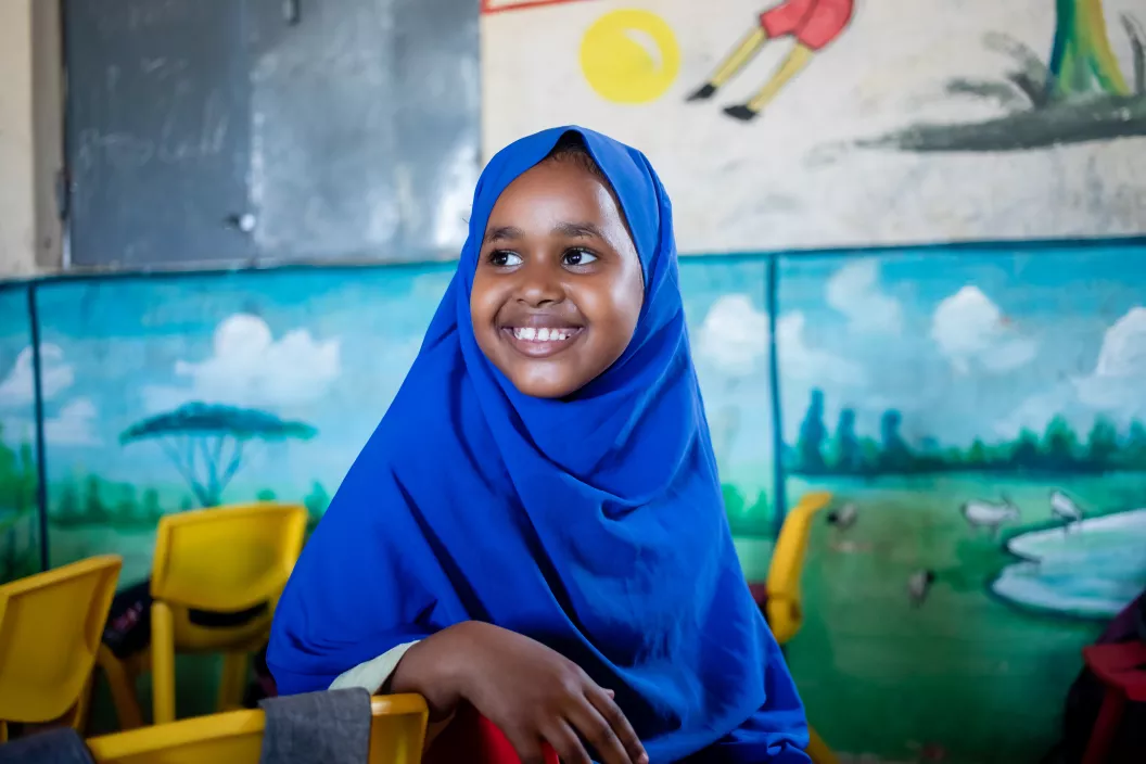 Young girl, wearing a hijab, sitting in her classroom and smiling