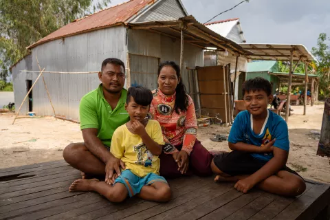 A family of four sits outside their home on the Mekong river, Cambodia.