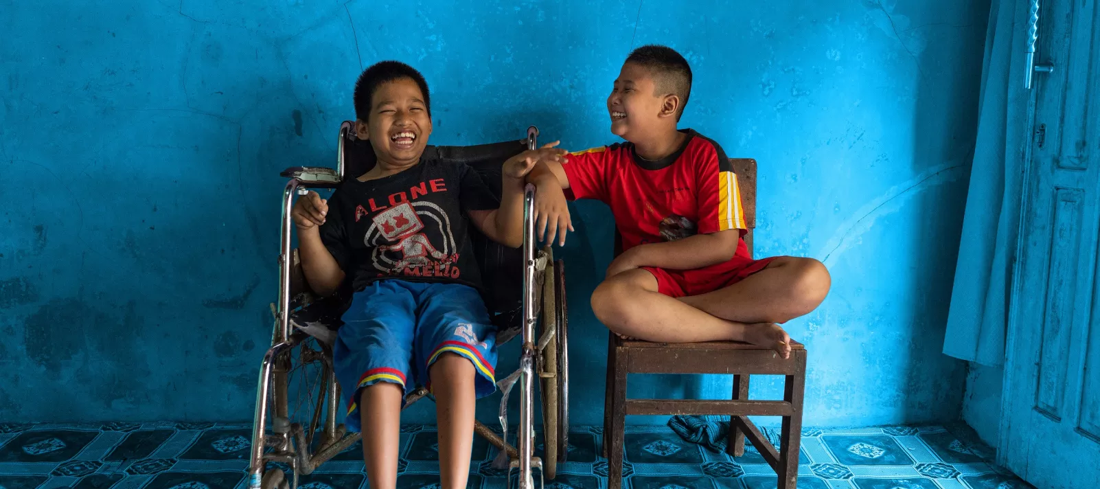 A child with a physical impairment sits next to his best friend.