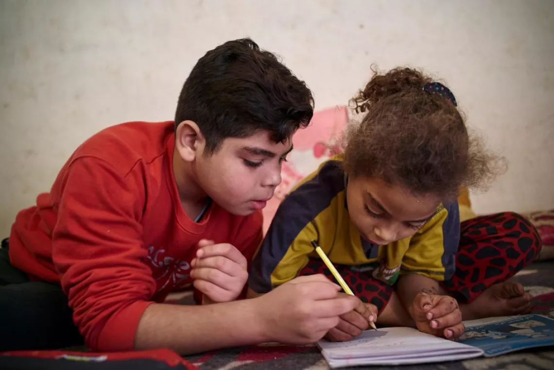 Abdelrahman (10 ans), aide sa petite sœur de 6 ans, Mai, à faire ses devoirs dans un bidonville d’Ezbet Khairallah, au Caire.
