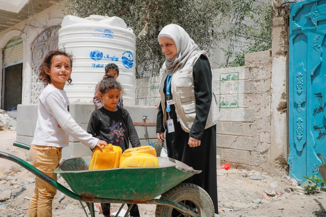 الكاتبة ميسون الحاج عمر تتجاذب أطراف الحديث مع أطفال ينتظرون شاحنات صهريجية لملء أوعية تخزين المياه في صنعاء.