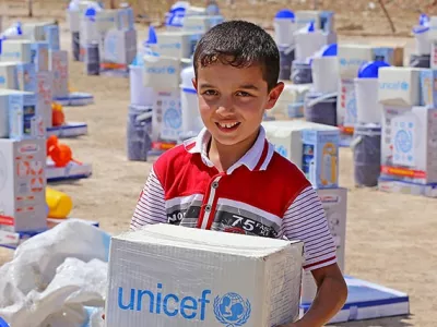 A boy picks up part of an emergency supply kit provided by UNICEF at a distribution in Diwaniyah, Iraq, in Augusto 2015.